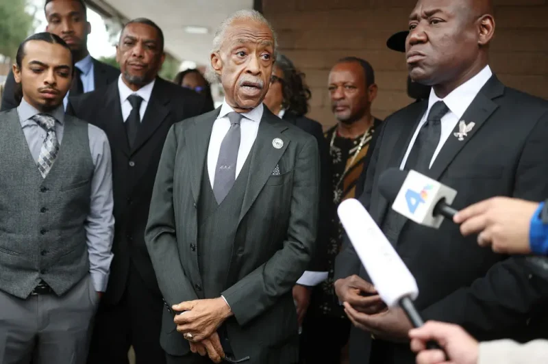 PASADENA, CALIFORNIA - FEBRUARY 06: Reverend Al Sharpton (C) and civil rights attorney Ben Crump (R) speak to the media as Trevor Kelley (3rd L) and Trevor Kelley Jr. (L), son and grandson of Erliene Kelley who died in the Eaton Fire, look on before a memorial service for area wildfire victims at First AME Church on February 6, 2025 in Pasadena, California. At least 29 people were killed and over 12,000 structures, many of them homes and businesses, were destroyed in the Eaton and Palisades Fires. (Photo by Mario Tama/Getty Images)